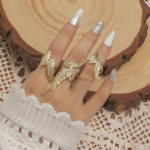 Gouden veren ringenset met kettingen en strass steentjes op een houten achtergrond