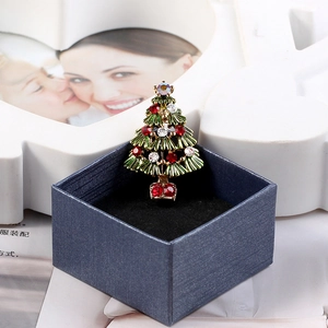 Detailed view of a green Christmas tree brooch with colorful rhinestones in a blue gift box