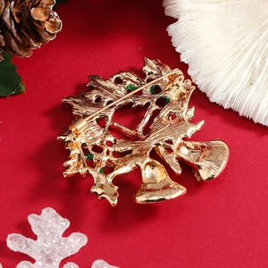 Christmas wreath brooch with bells and green enamel details on vibrant red background