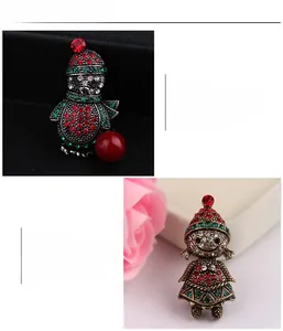 Detail view of rhinestone-encrusted Christmas penguin and girl brooches with festive red gems