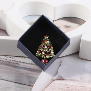 Close-up of golden Christmas tree brooch with colorful rhinestones in a blue gift box
