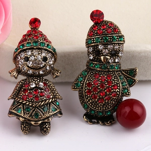 Close-up of vintage gold Christmas brooches featuring girl and penguin with red and green rhinestones