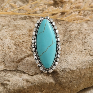 Vintage bohemian turquoise ring with rhinestone halo set on a textured stone background