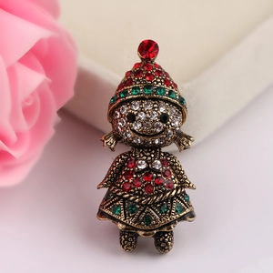 Close-up of a vintage Christmas doll brooch with red and green rhinestones on bronze base