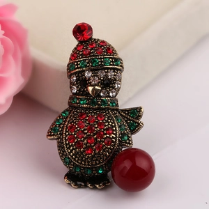 Macro shot of vintage gold penguin brooch with colorful rhinestones and red pearl