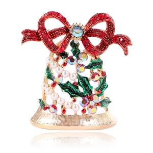 Detailed view of Christmas bell brooch with red rhinestones and green holly leaves