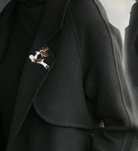 Vue détaillée d'une broche renne en émail avec bois dorés et perle sur un revers de manteau