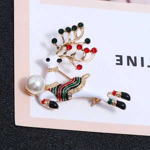 Détail d'une broche cerf de Noël en émail blanc avec perles et strass colorés étincelants