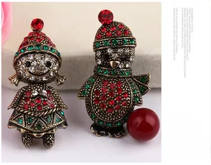 Macro detail of Christmas girl and penguin brooches with vintage gold plating and rhinestones