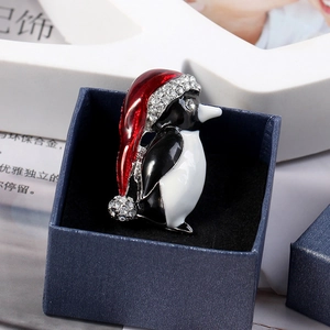 Détail de la broche pingouin de Noël avec émail et strass brillants dans une boîte bleue