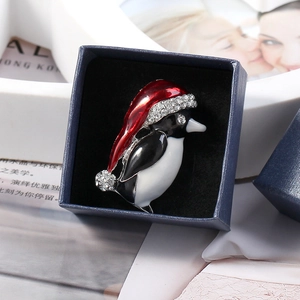 Vue macro d'une broche pingouin de Noël avec bonnet rouge dans un coffret cadeau bleu