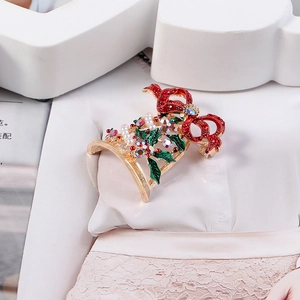 Detail showing Christmas bell brooch with red crystal bow and green holly enamel