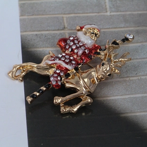 Macro detail of a crystal Santa Claus on reindeer brooch with gold plating and red enamel