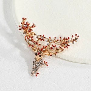 Détail d'une broche renne dorée avec fleurs en émail rouge et accents en cristal blanc