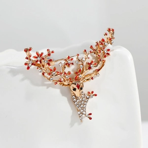 Détail de la broche renne doré avec des strass étincelants et de l'émail rouge vif