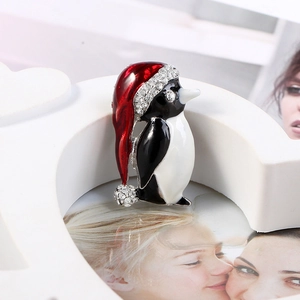 Détail d'une broche pingouin de Noël avec chapeau en émail rouge et strass brillants