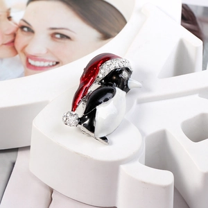 Détail macro de la broche pingouin de Noël avec bonnet émaillé et strass brillants
