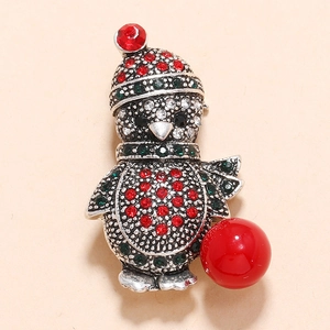 Christmas penguin brooch with rhinestones and a large red pearl on a light background