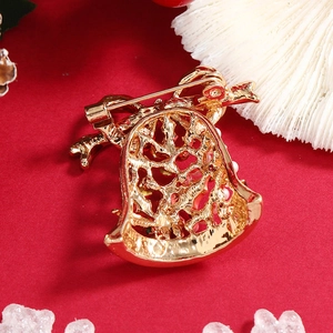 Christmas bell brooch featuring intricate golden metal hollow patterns and festive red accents