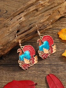 Detail of colorful turkey drop earrings in gold setting with festive autumn leaves decor