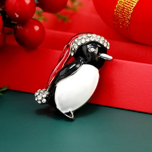 Broche pingouin de Noël en émail noir et blanc avec bonnet rouge sur fond festif