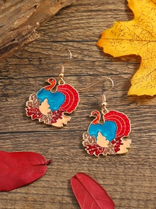 Macro detail of Thanksgiving turkey earrings with colorful enamel on a rustic wood background