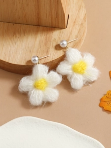 Detail of plush white flower earrings with yellow centers and elegant pearl studs