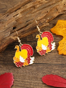 Detailed close-up of turkey earrings featuring colorful enamel on a fall leaf background