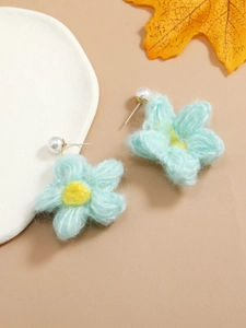 Detailed view of light blue knitted flower earrings with a white pearl stud accent