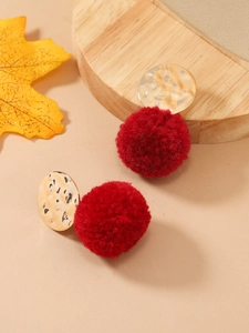 Detail van rode fluwelen pompon oorbellen met gehamerde gouden studs in herfststijl