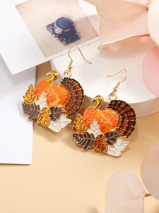 Close-up of golden turkey and maple leaf drop earrings with colorful enamel details