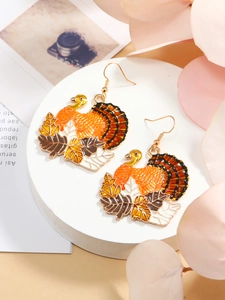 Detail of turkey and maple leaf earrings with vibrant autumn colors and gold hooks