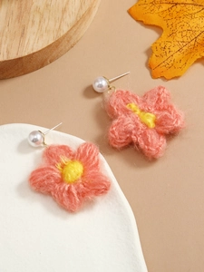 Detailed macro view of handmade crochet flower earrings with pink petals and a white pearl