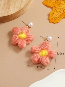 Close-up of knit flower earrings with 5cm size scale on natural wood background