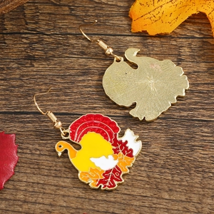 Festive turkey drop earrings in colorful alloy on a warm autumn wooden background