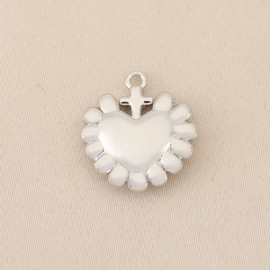 Macro shot of silver heart pendant with petal edges and a small cross connector charm