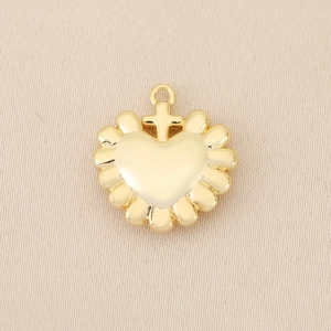 Macro detail of 18k gold plated heart pendant with central cross and relief edge