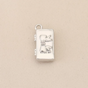 Close-up of a silver polished 18k gold plated square pendant with 3D bow design