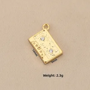 Vista macro detallada del colgante de cassette retro bañado en oro 18k con circonitas incrustadas