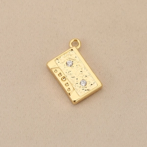 Detalle de colgante de casete vintage con baño de oro de 18k y circonitas blancas pequeñas