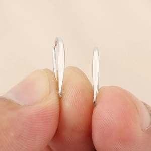 Detalle macro de ganchos para pendientes plateados geométricos que muestra grosor y brillo