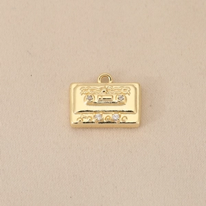 Primer plano de un colgante de casete retro bañado en oro 18k con circonitas