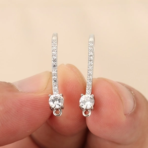 Detailed macro view of U-shaped silver ear hooks with rhinestones and circular loop