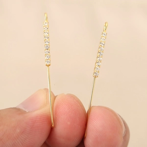 Dettaglio di orecchini a barra placcati oro 18k con fila di zirconi scintillanti