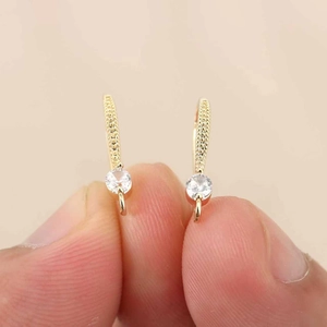 Detalle del gancho de oreja de cobre bañado en oro de 18k con circón redondo en mano