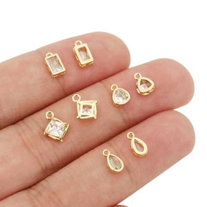 Hand holding 18k gold plated geometric zircon pendants in square and teardrop shapes