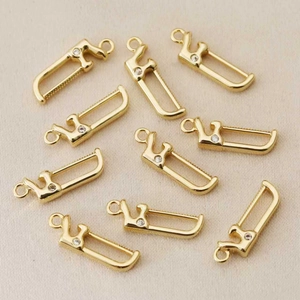 Détail de 10 pendentifs scie évidés plaqués or avec zircon sur tissu texturé