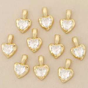 Detalle de diez colgantes de corazón chapados en oro 18k con piedras de circonita clara