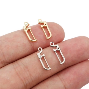 Gros plan de mini pendentifs scie en or et argent pour la fabrication de bijoux DIY