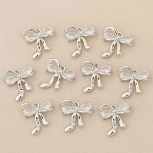 Detalle de colgantes de lazo plateado con circonitas para creación de joyas DIY